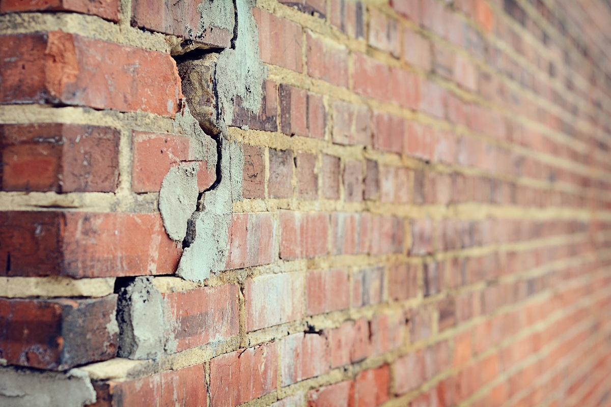 A wall of a house with bricks that have cracks in them